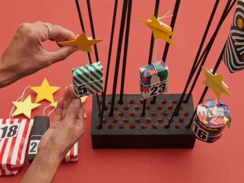 Mit den Sternenklammern die Päckli an den Holzstäben verteilen. Die schwereren Geschenke an den dickeren Stäben und eher unten platzieren.